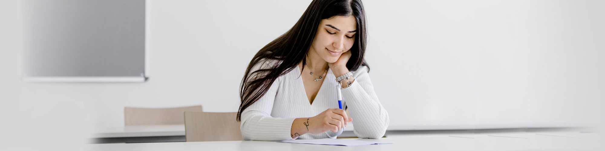 junge Frau bei einer Prüfung am Schreibtisch sitzend
