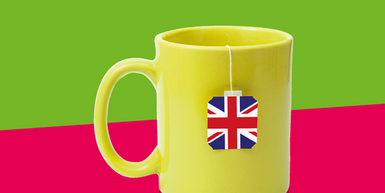 Gelbe Teetasse mit Britischer Flagge vor grün-rotem Hintergrund