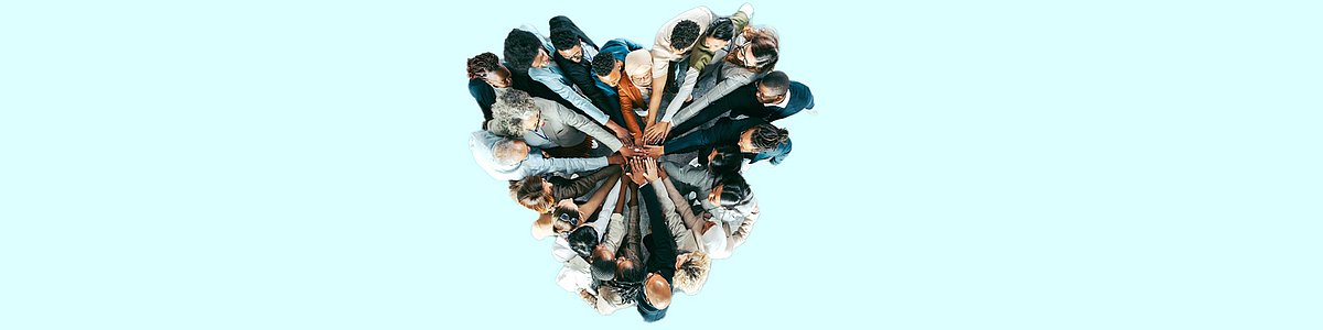 Foto: Gruppe von Menschen, die in der Mitte die Händen zusammenlegen und dabei ein Herz formen
