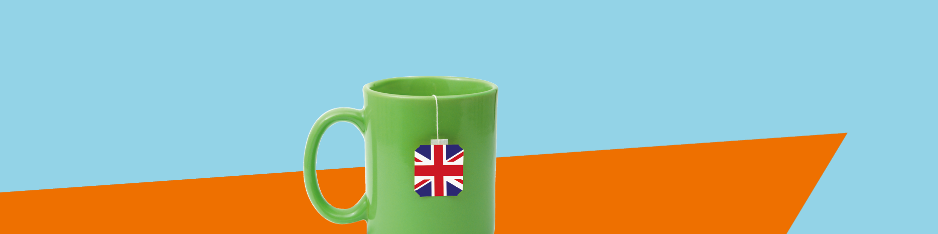 grüne Tasse mit englischem Teebeutel vor orange-hellblauem Hintergrund
