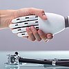 Foto: menschliche Hand schüttelt Roboter-Hand, darunter liegt ein Stethoskop