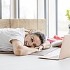 Foto Frau bei Yogaübung auf dem Bauch liegend mit Laptop