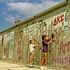 Berliner Mauer mit Jugendlichen, die Stücke aus der Mauer schlagen
