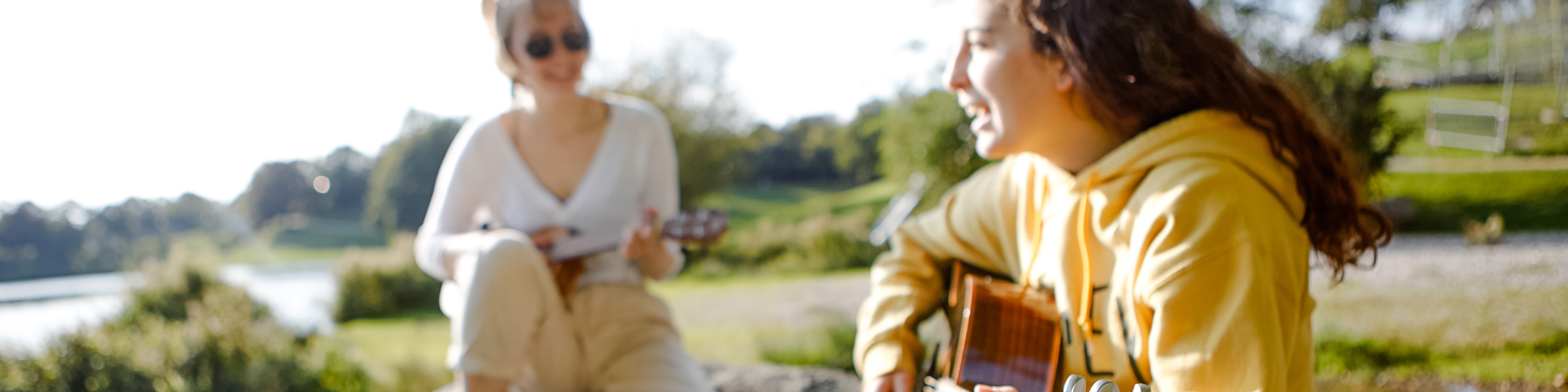 Foto: Zwei junge Frauen spielen im Park Gitarre