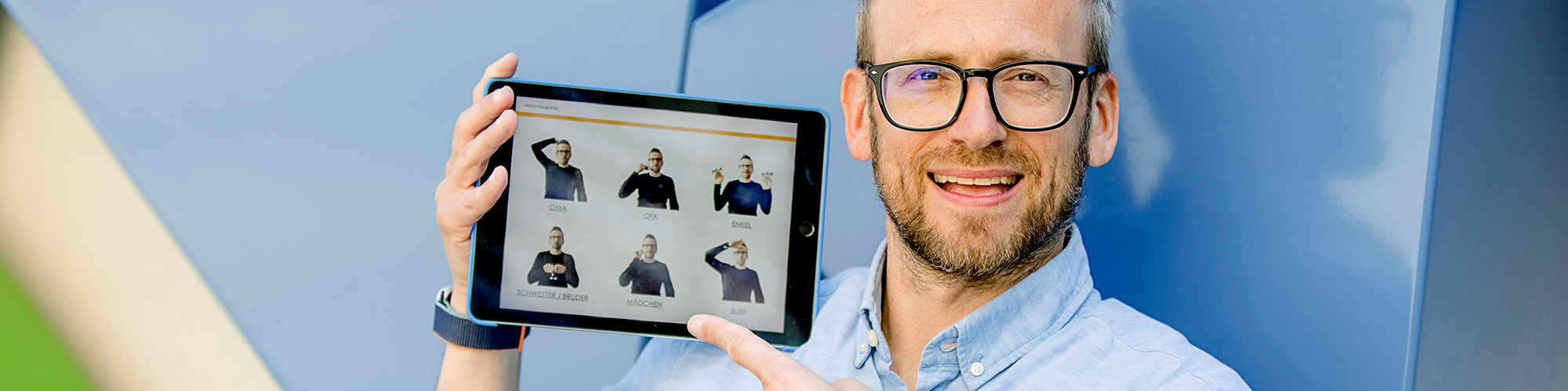 Engagierter Dozent für Gebärdensprache zeigt das Fingeralphabet auf einem Tablet 