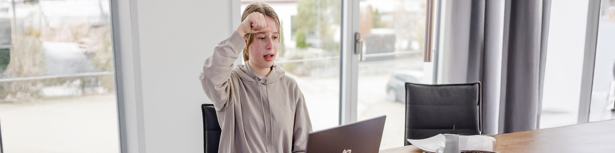 Teilnehmerin vor einem Laptop gebärdet ein Zeichen in Gebärdensprache