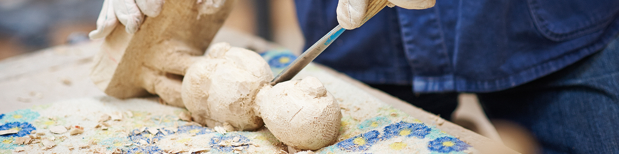 Teilnehmender bearbeitet eine kleine Figur aus Holz