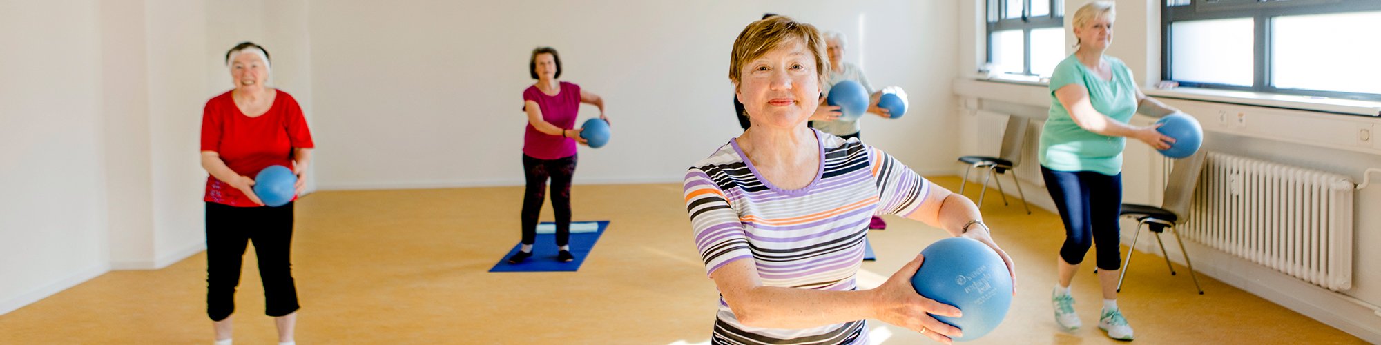 Aktive Seniorinnen üben mit Bällen in einem Gesundheitskurs 