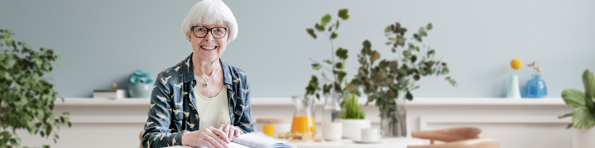 Ältere Dame an einem Cafétisch blättert interessiert in einem Heft