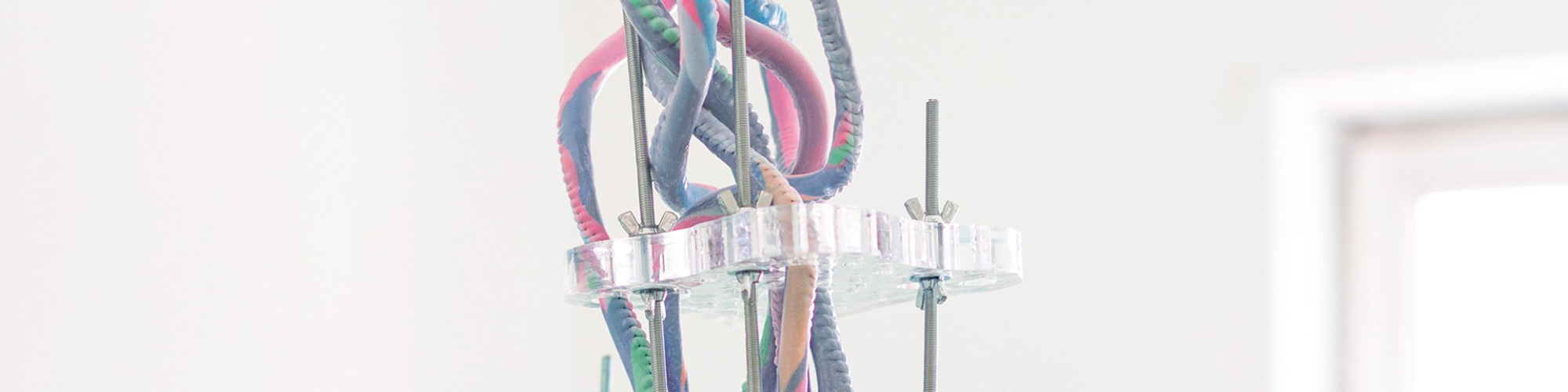 Detail einer abstrakten Skulptur des Künstlers Leo Heinik aus pastellfarbigen Stoffwürsten, Schrauben und 3D-Drucken