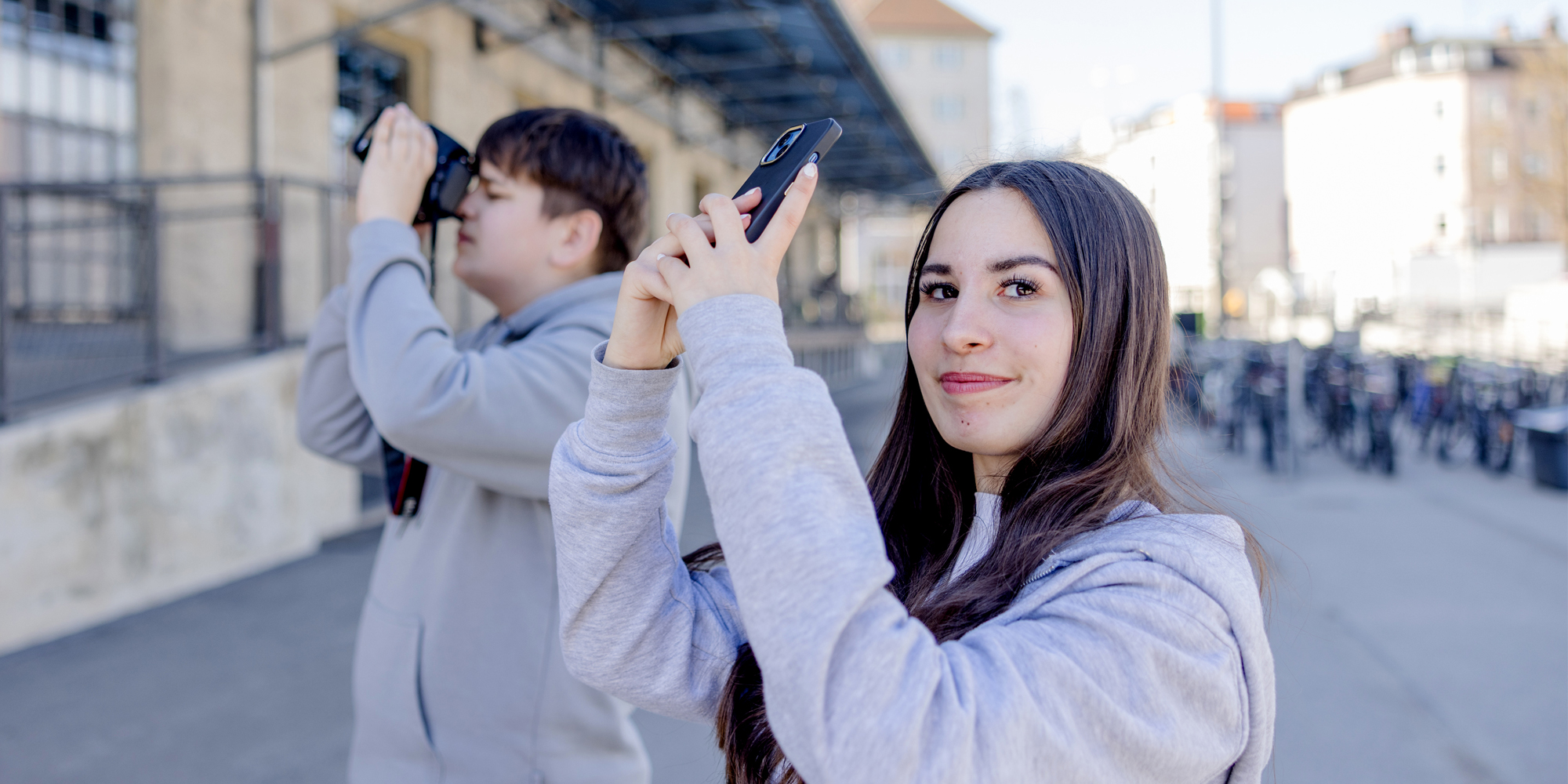 Foto junger Mann und junge Frau halten Kamera und Handy in die Luft