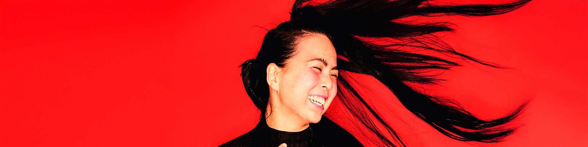 Foto: Hanni Liang mit wehenden Haaren vor rotem Hintergrund
