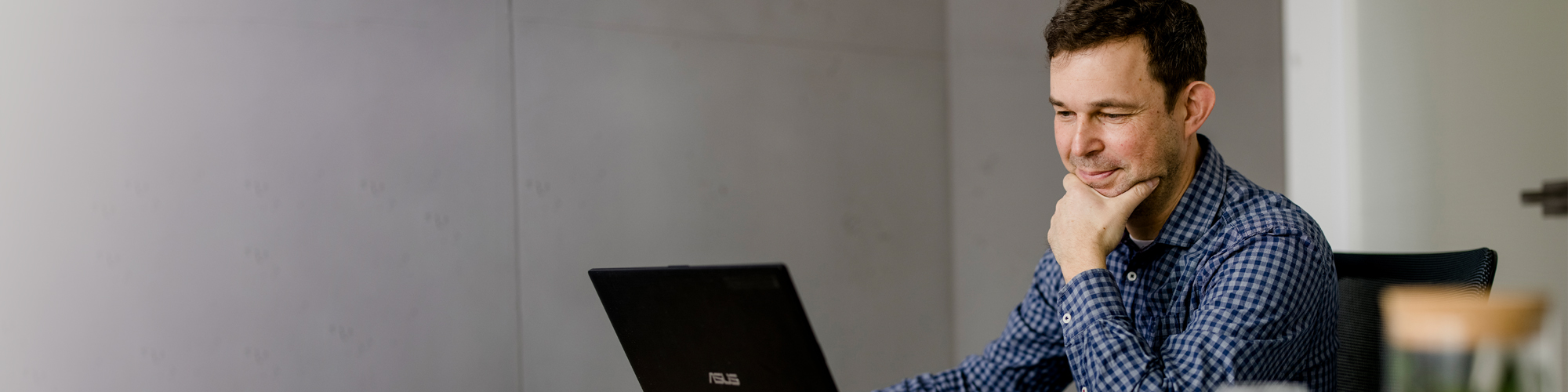 Junger Mann am Schreibtisch vor Laptop 