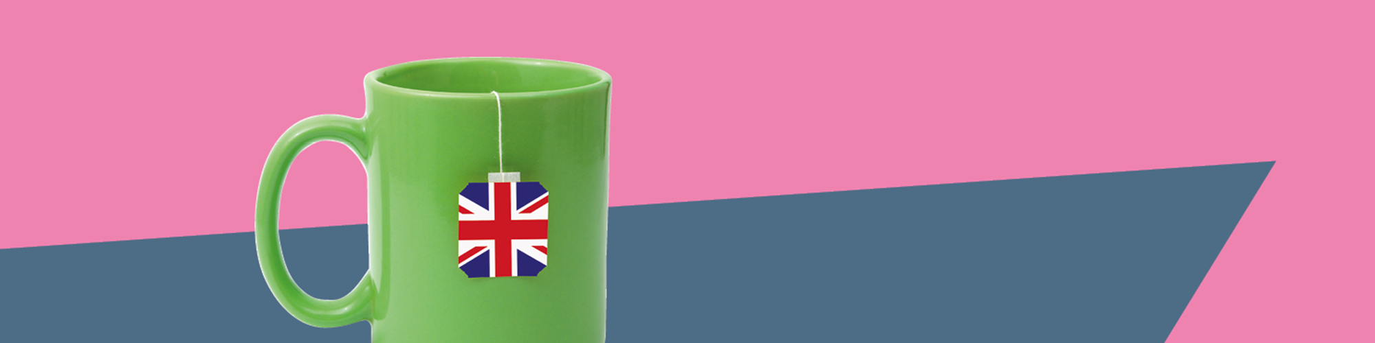 grüne Tasse mit englischem Teebeutel vor rosa-grauem Hintergrund